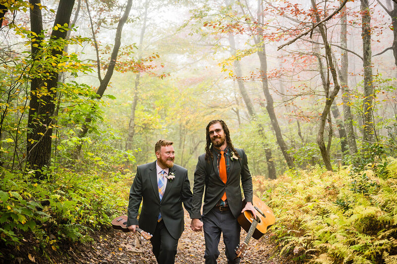 A gay couple walk hand-in-hand in a foggy forest during their fall elopement wedding day at Shenandoah National Park.