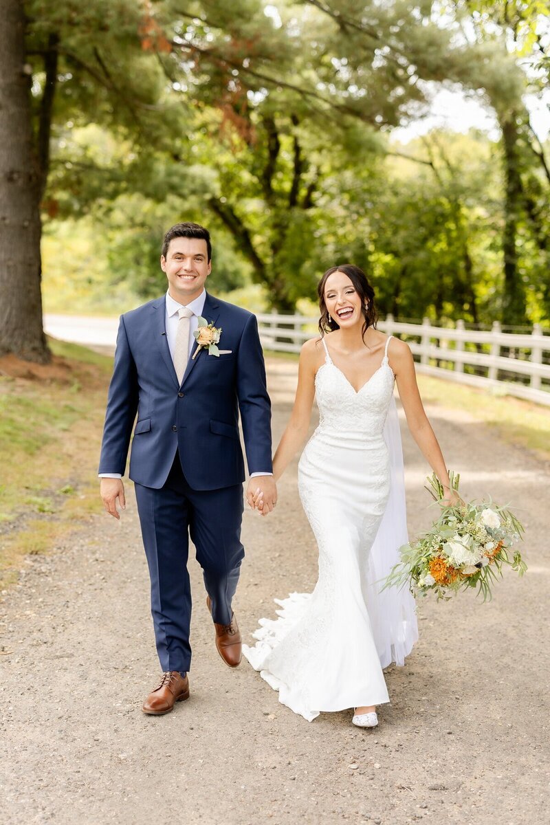 Bride and groom walking, laughing, and holding hands, taken by st paul wedding photographers, Kacey Wyrick