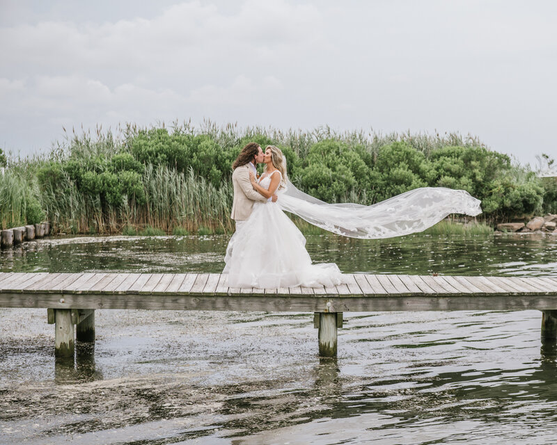 A classic and timeless wedding  photo featuring a kiss and a cathedral vail on the dock at Bonnet Island Estate 