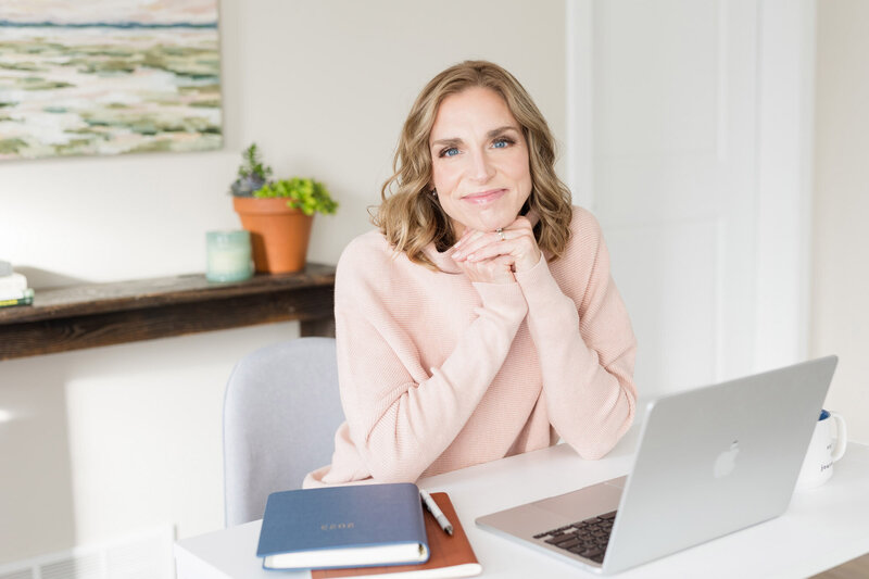 Stephanie, a Madison therapist, smiling in her office with her hands gently folded under her chin