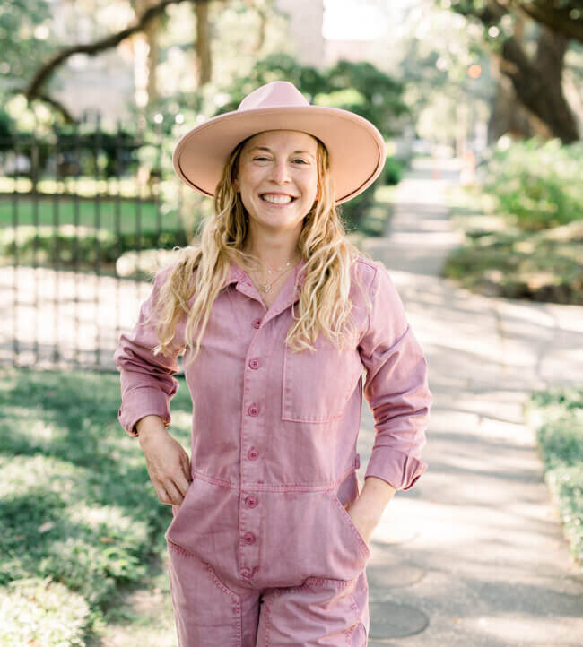 On Brand By Sarah's Tiktok and Instagram Client, Alyssa, Smiling with arms outstretched, wearing a pink jumpsuit