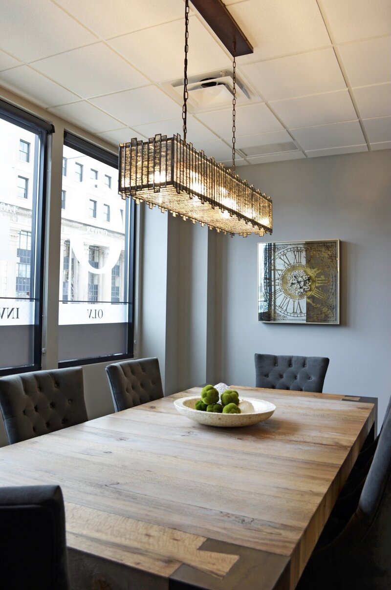 Conference room  with a large wooden table and dark grey tufted upholstered chairs