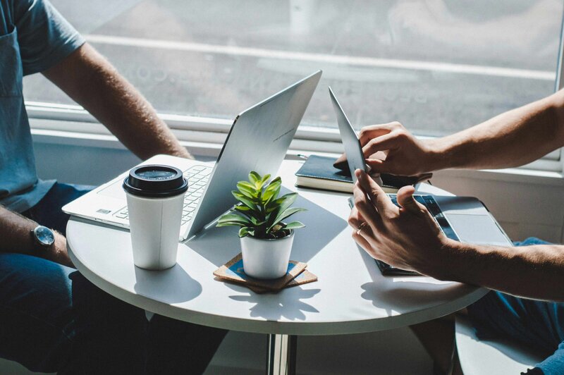Two people working at a cafe with their laptops.