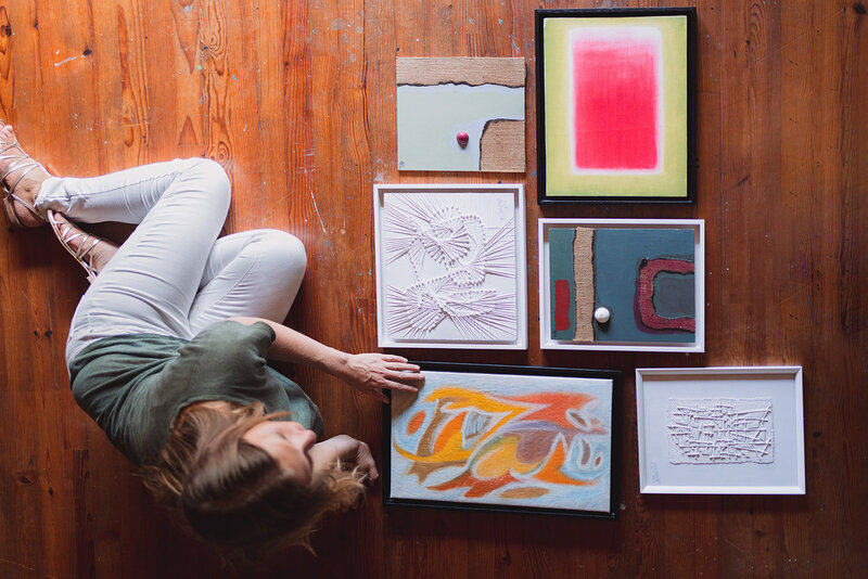 Lou dans l'atelier avec plusieurs tableaux posés au sol