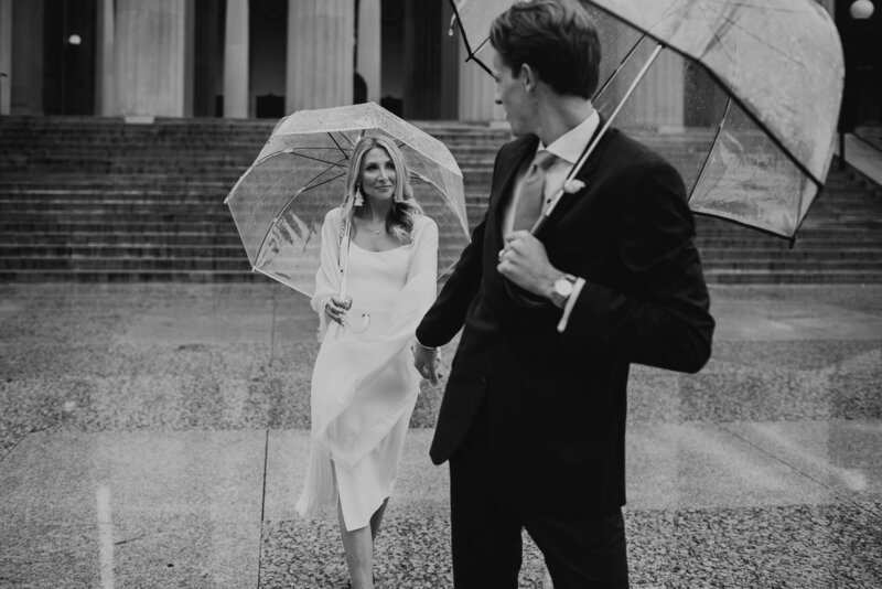 bride and groom holding hands and umbrellas
