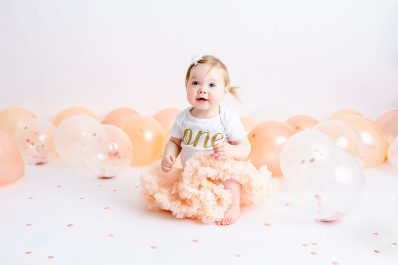 one year old girl posing for portraits for a cake smash session