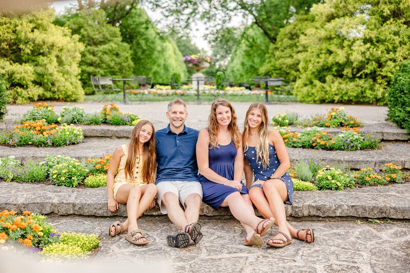 Family in blue and yellow sitting on the steps garden at Wegerzyn Gardens