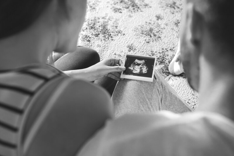 Couple sitting closely together looking down at a picture of an ultrasound image – representing relationship support for pregnancy and infant loss with Freedom Couple Counselling in Melbourne.