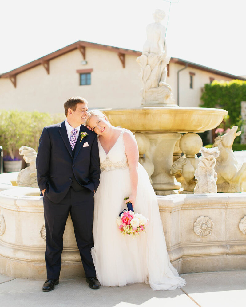 Bride leans head on Groom holding her bouquet as Groom looks off to his left