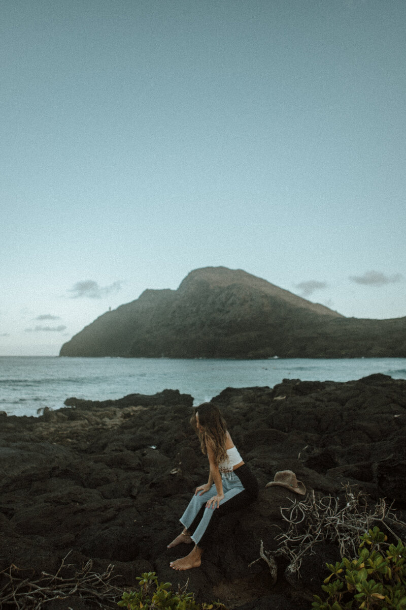 Jenna Guyot looking out to the water holding her hat