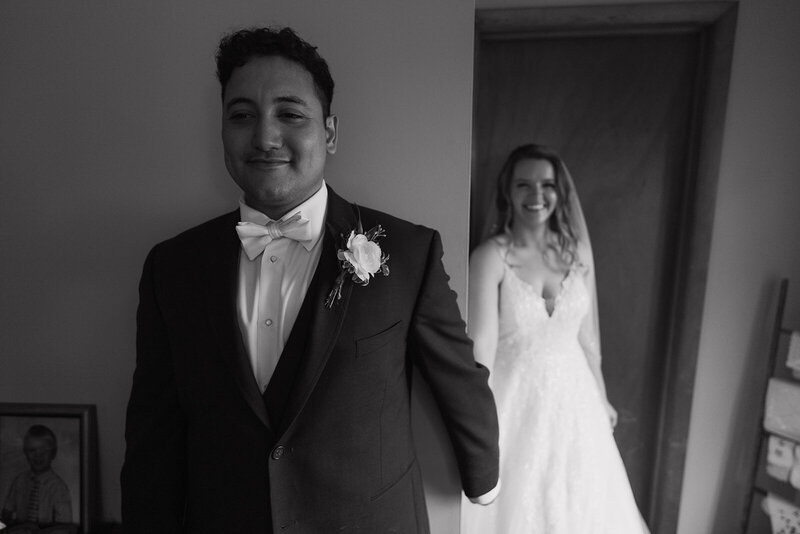 The groom stands with his back to the bride, holding her hand.