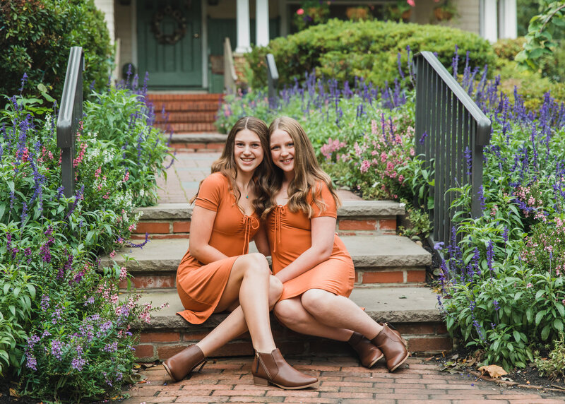 Portrait of sisters posed sitting on steps in a New Jersey park.