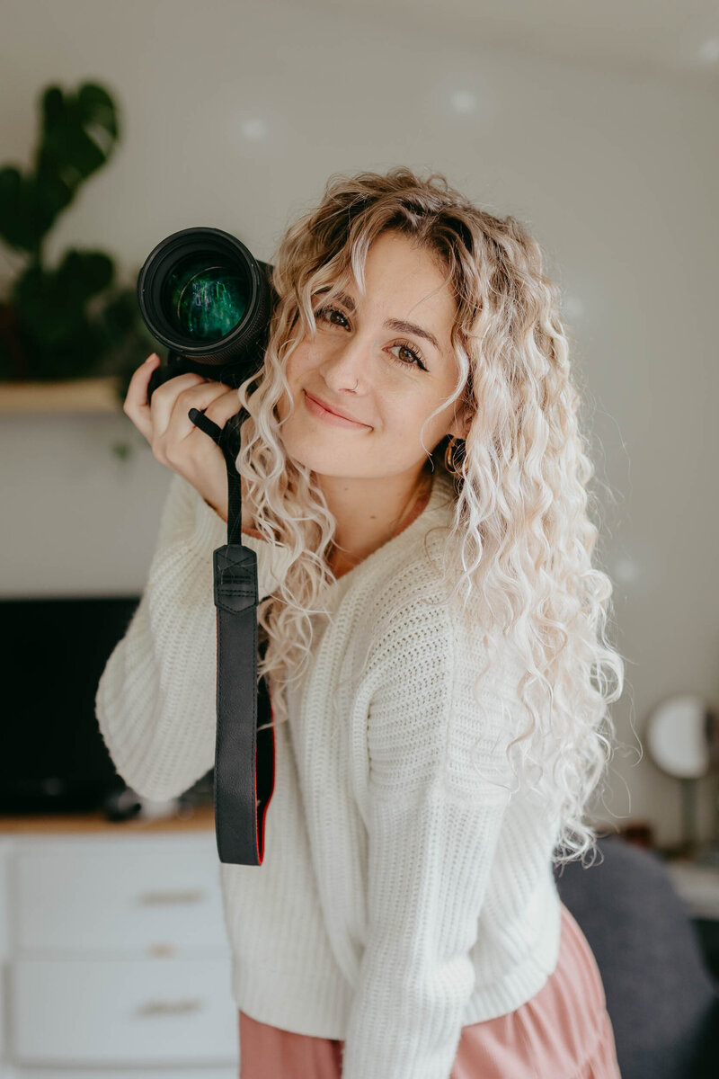 Portrait of Alexx, the photographer for Lexx Creative, holding a camera