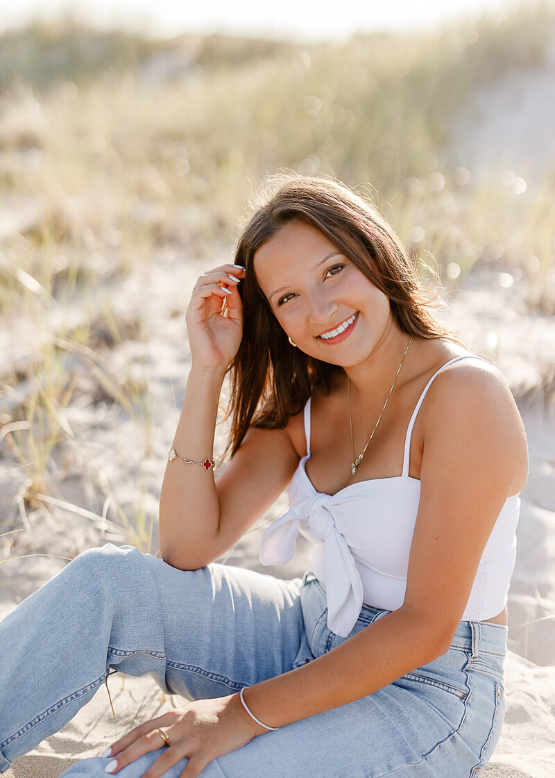 Photo by South Shore Photographer Christina Runnals | A high school senior standing in front of a fence smiling at the camera for her senior portraits