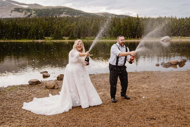 Bride and groom spray champagne and Coke after their Brainard Lake elopement with Colorado elopement photographer and videographer packages Alpine Vows.