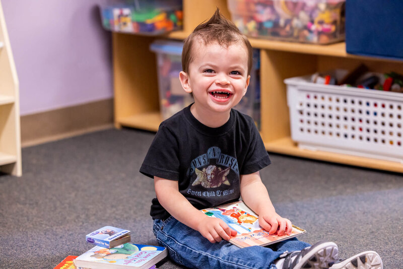 happy toddler boy reading a book at daycare