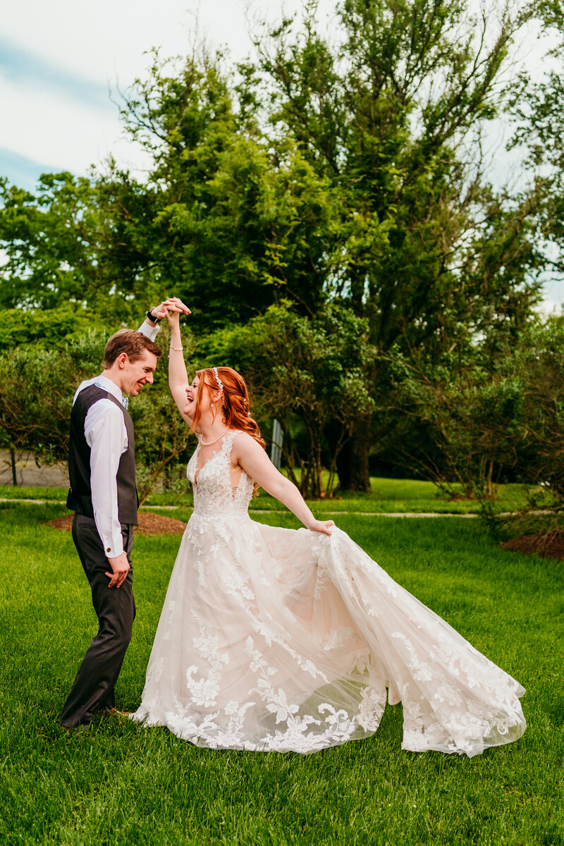 Joyful bride and groom dancing outdoors on lush green lawn during their elopement day.
