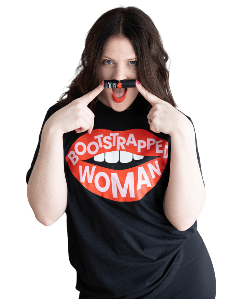 Emily, a brand and web designer, wearing a "Bootstrapped Woman" t-shirt while holding a tube of lipstick under her nose.