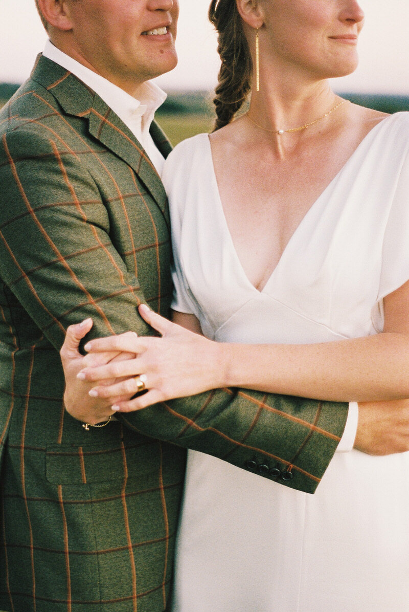 Groom in plaid suit jacket hugging bride in whimsical gown