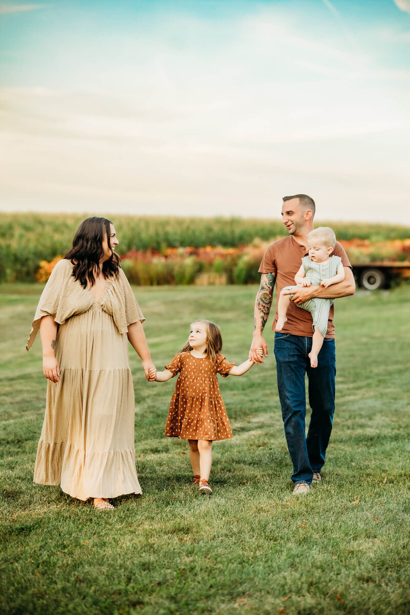 Family walking together holding hands in front of flower field during their Harrisburg photography session