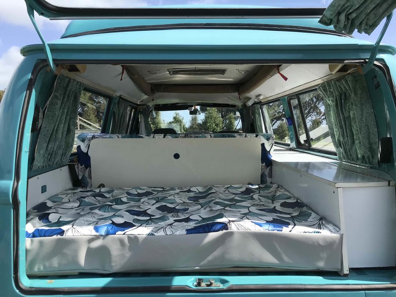 View of back door open showing bedding of Rhonda, teal retro kombi van from NZ Kombi Hire