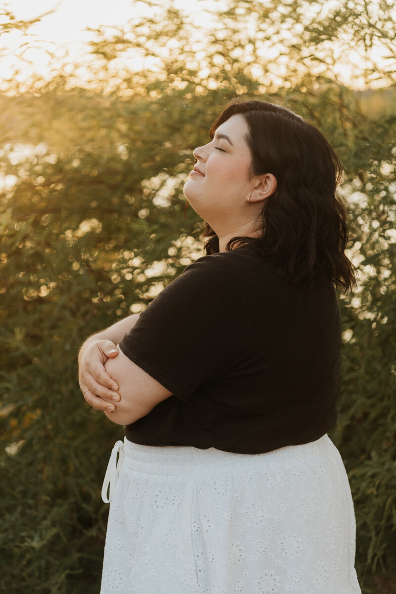 A person smiling and lifting their chin up towards the sky 