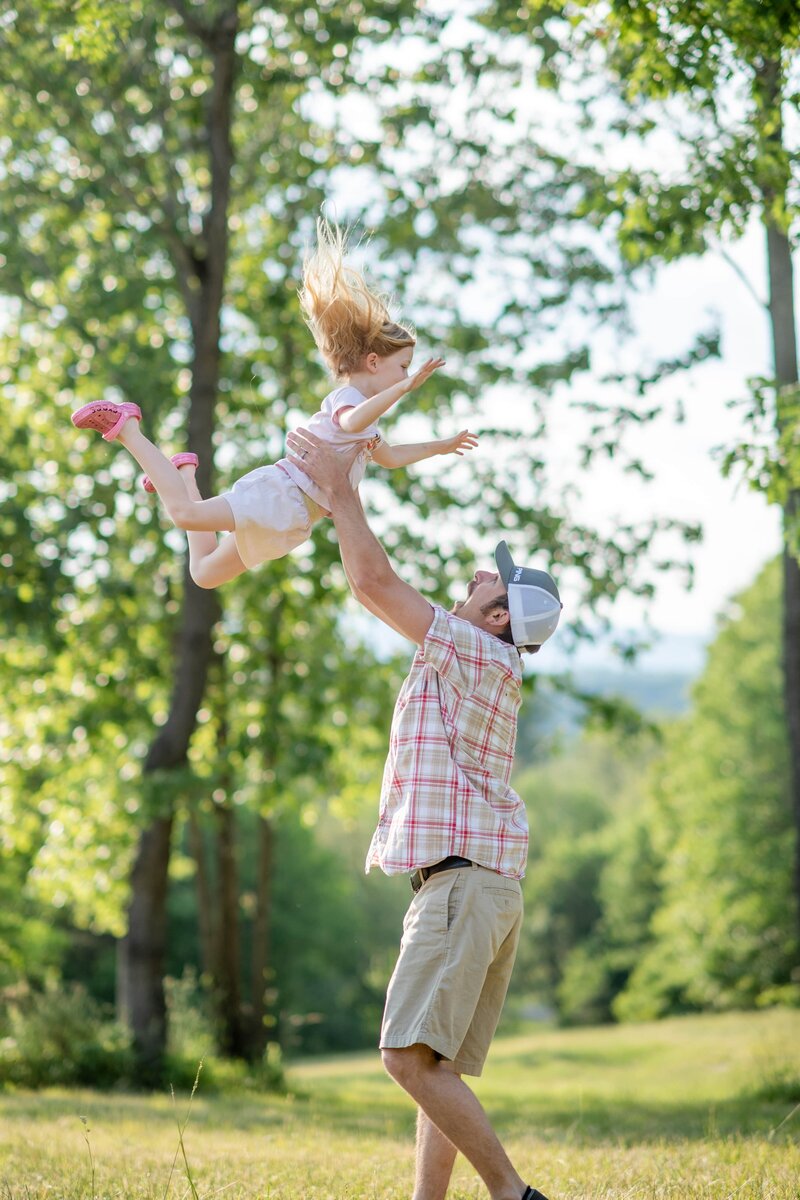 Playful Dad tossing daughter in the air