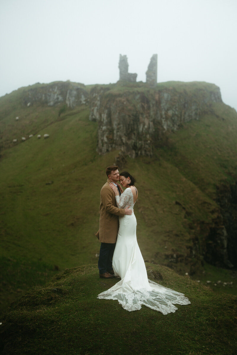Hiking wedding with castle ruins and sheep, couple is hugging in the cold