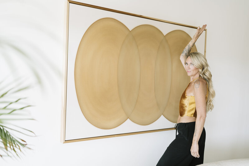 Aine Rock in a gold top against a gold painting 