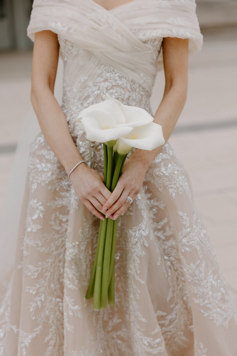 A close up of someone in a wedding dress holding a bouquet of flowers 