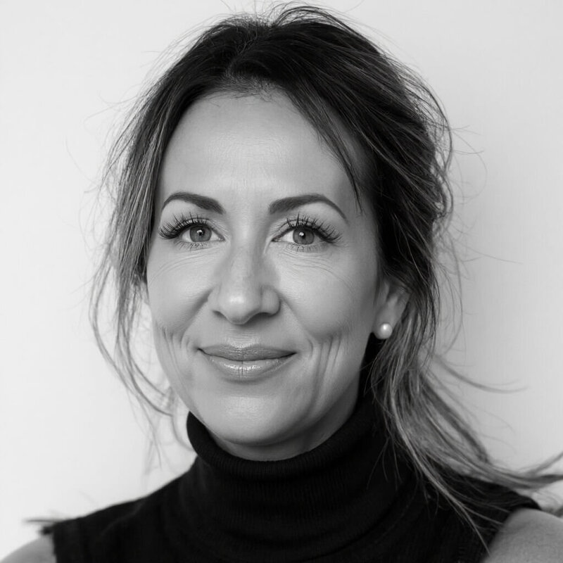 Black and white portrait of a woman with long hair pulled back, wearing a sleeveless turtleneck and pearl earrings, smiling at the camera—Cristina Horvath, CEO and creative web designer at Sweet Pea Ink Creative.