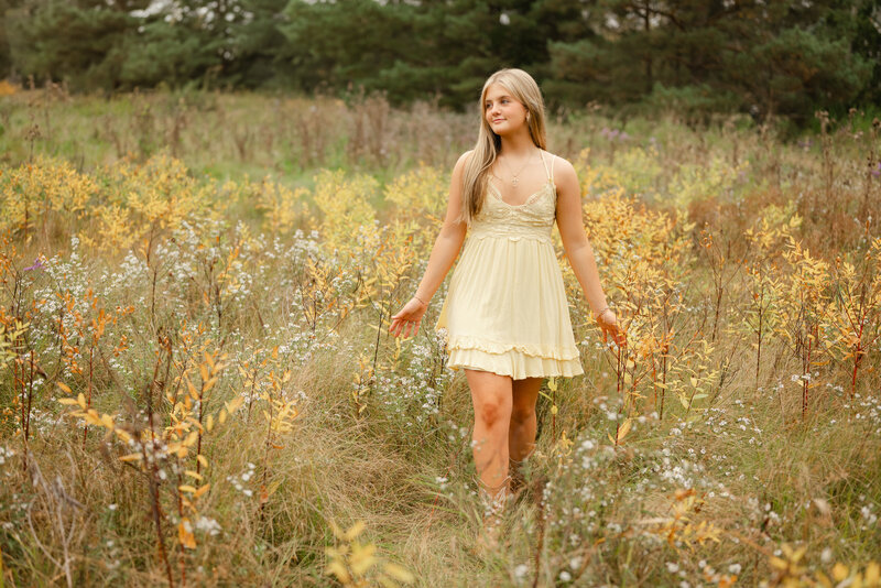 Senior graduation photo in a flower field with a yellow dress.