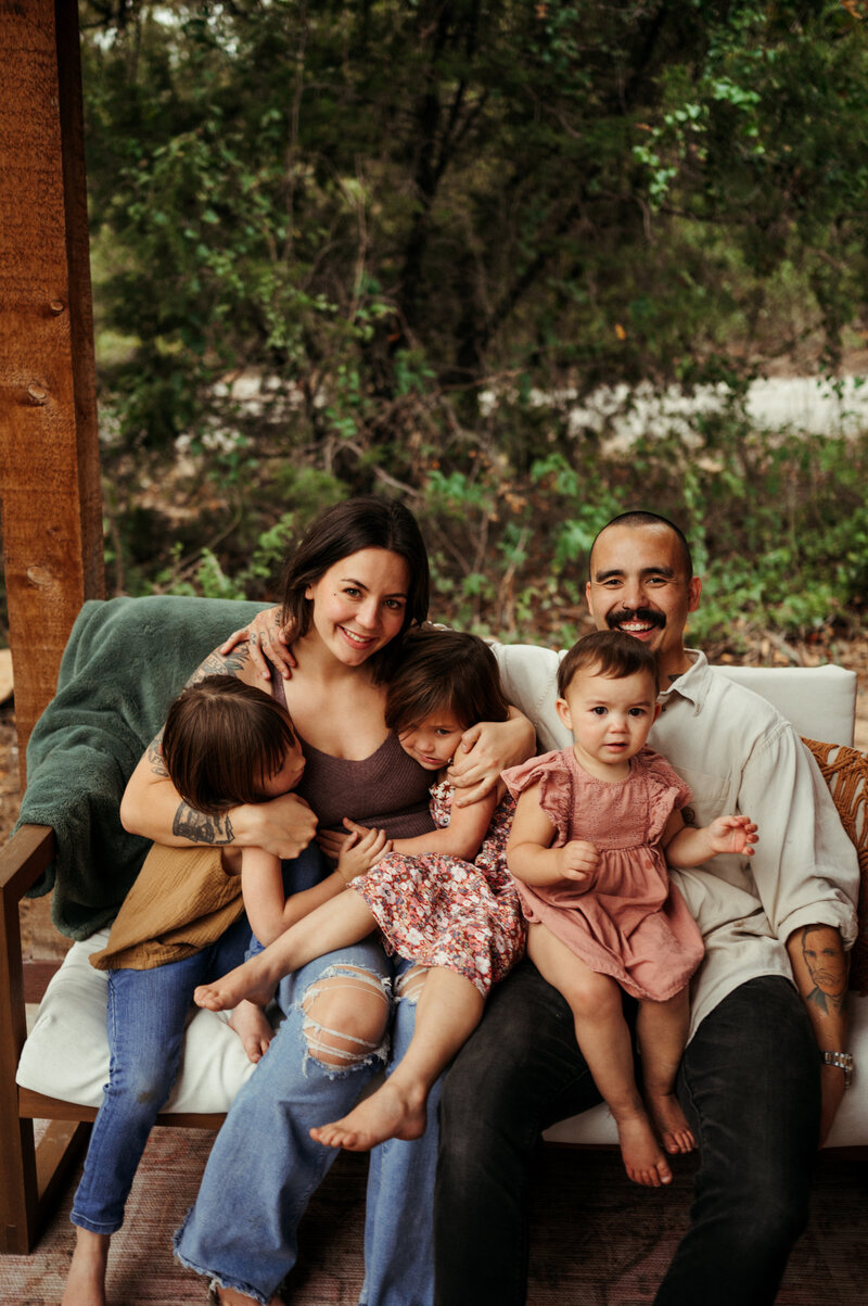Family of five snuggling up on a porch swing.
