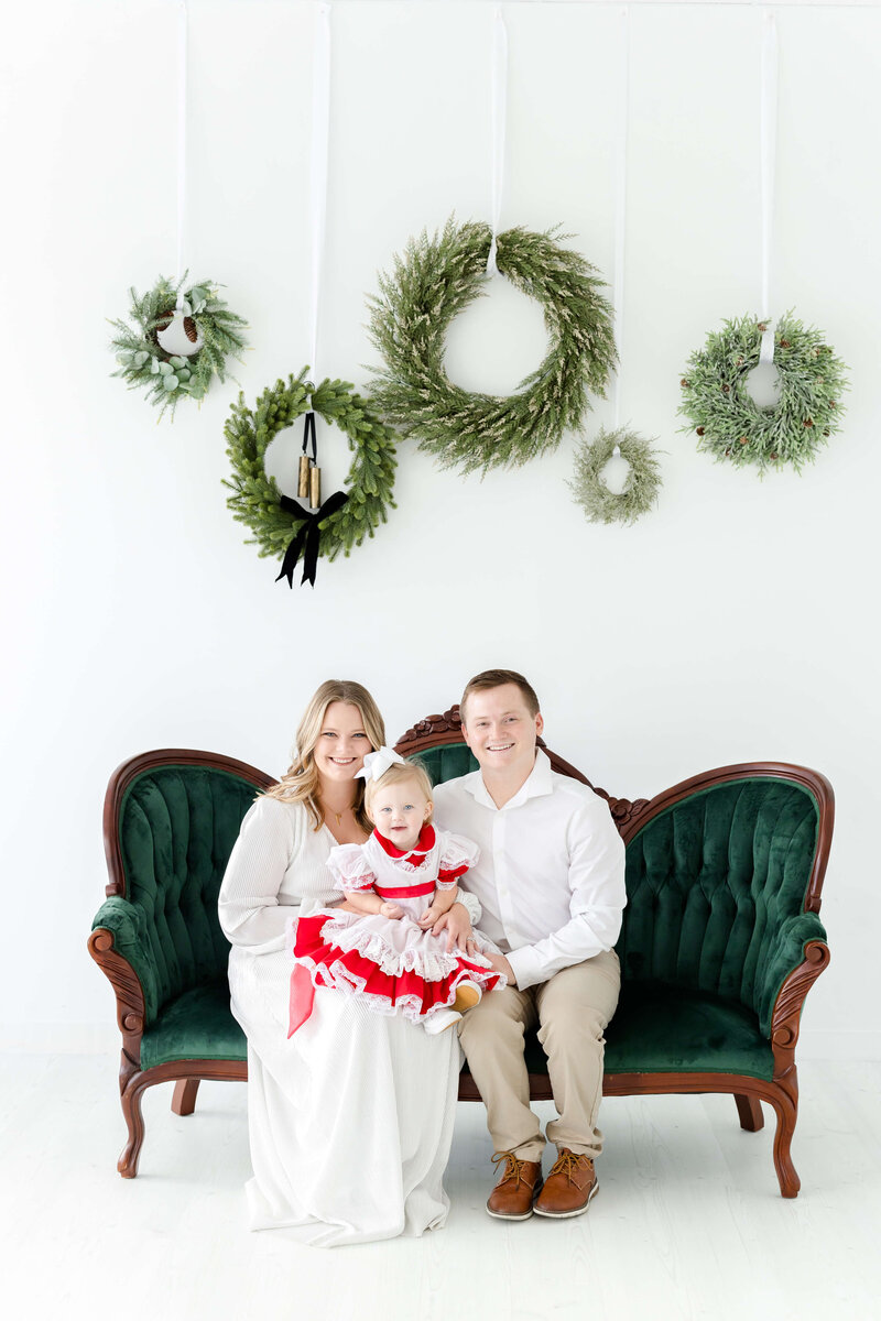 Family of 3 smiling at the camera for christmas mini session in dothan alabama