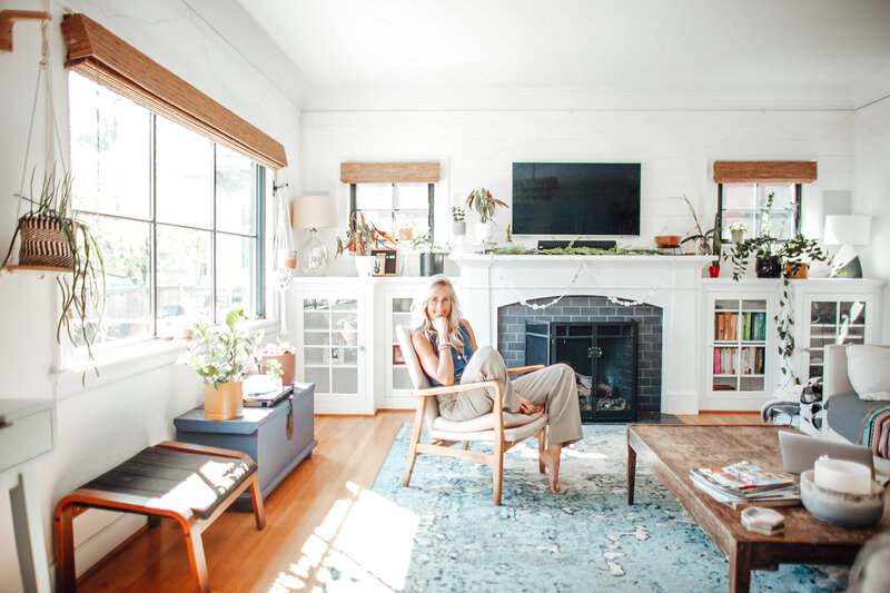 Portland OR realtor and relocation expert Stephanie sits in a chair in her living room with her chin resting on her fist.