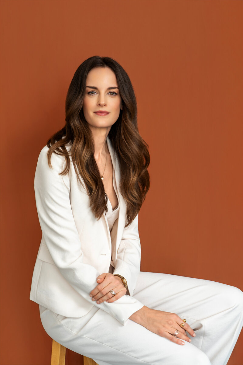 Lee Greene in white suit against burnt orange background