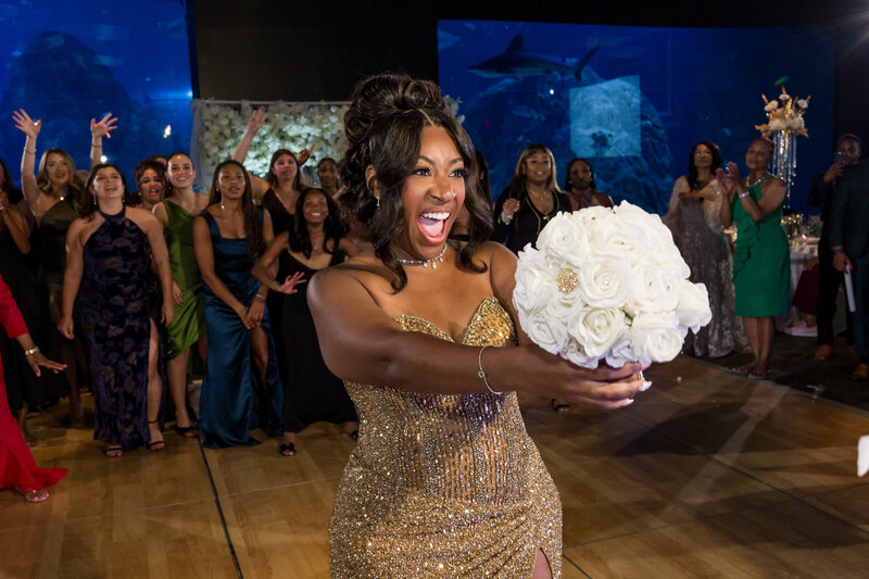 Bride getting ready to toss her bouquet in the elegant Currents Ballroom at Adventure Aquarium, surrounded by excited guests.