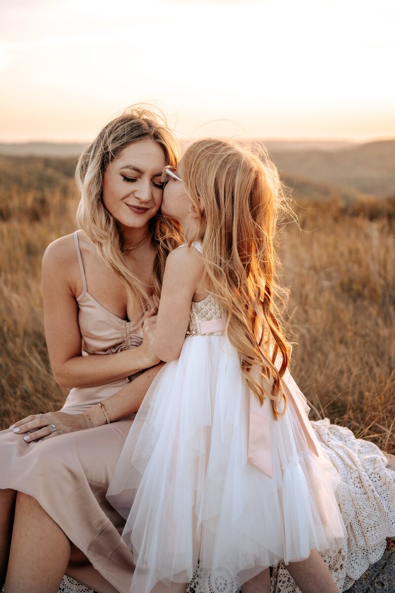 Girl giving mom a kiss on the cheek for family photos