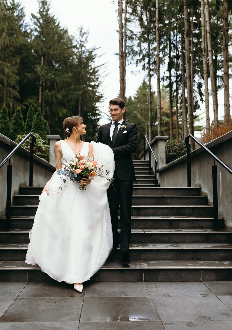 bride and groom walking down steps as groom holds her train