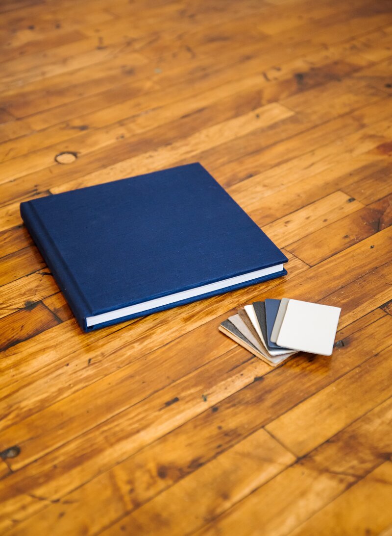 Image album displayed neatly on the floor, for branding photos along with album material samples.