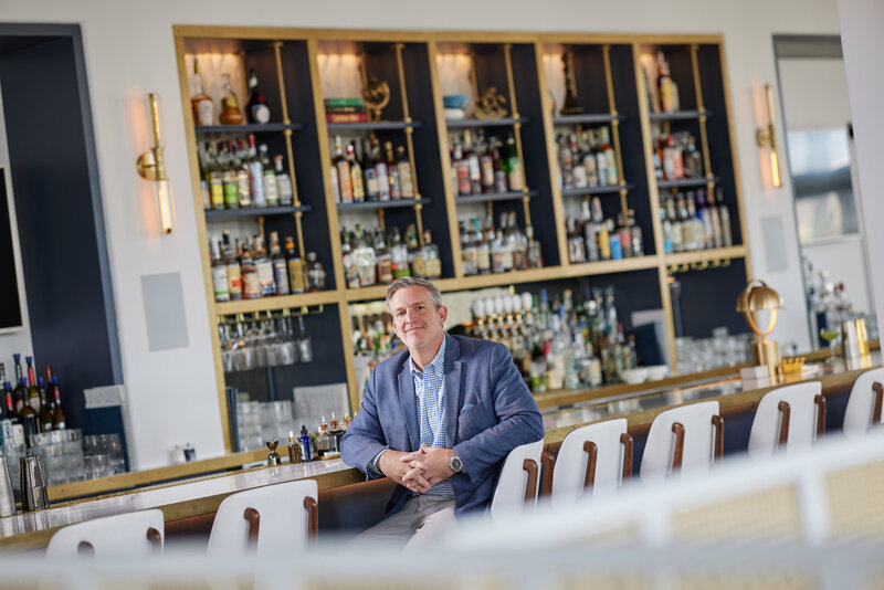 A person smiling as they sit at a bar.