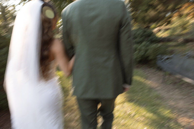 Bride and groom swiftly walk through golden hour lighting in the gardens of their wedding reception at Cheekwood. 