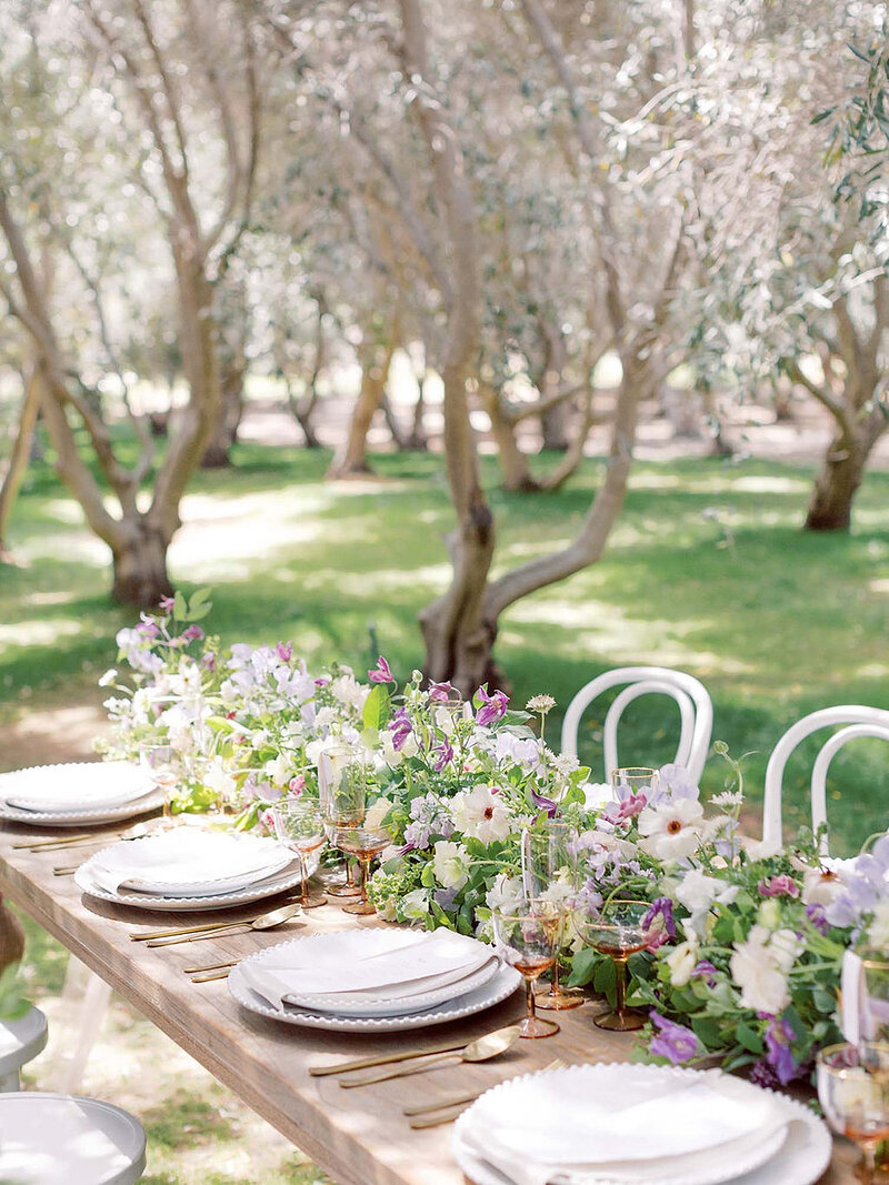 16-radiant-love-events-closeup-wooden-table-seating-of-8-plates-floral-table-runner-middle-of-olive-tree-orchard-outdoors-romantic-elegant-timeless