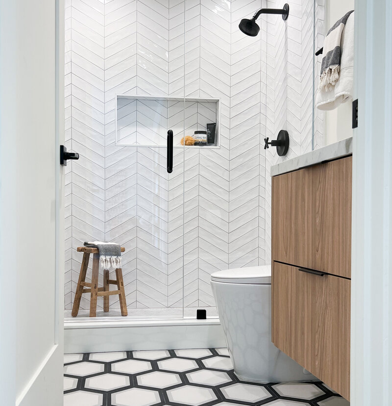 Small minimalistic white modern chevron bathroom tile design and black metal accents