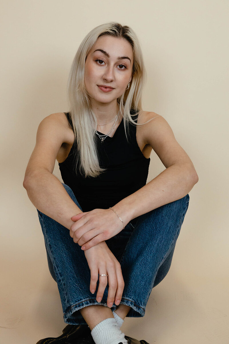 Clarae, a design and event planner in Oregon, sits with her arms across her knees and looks at the camera. 