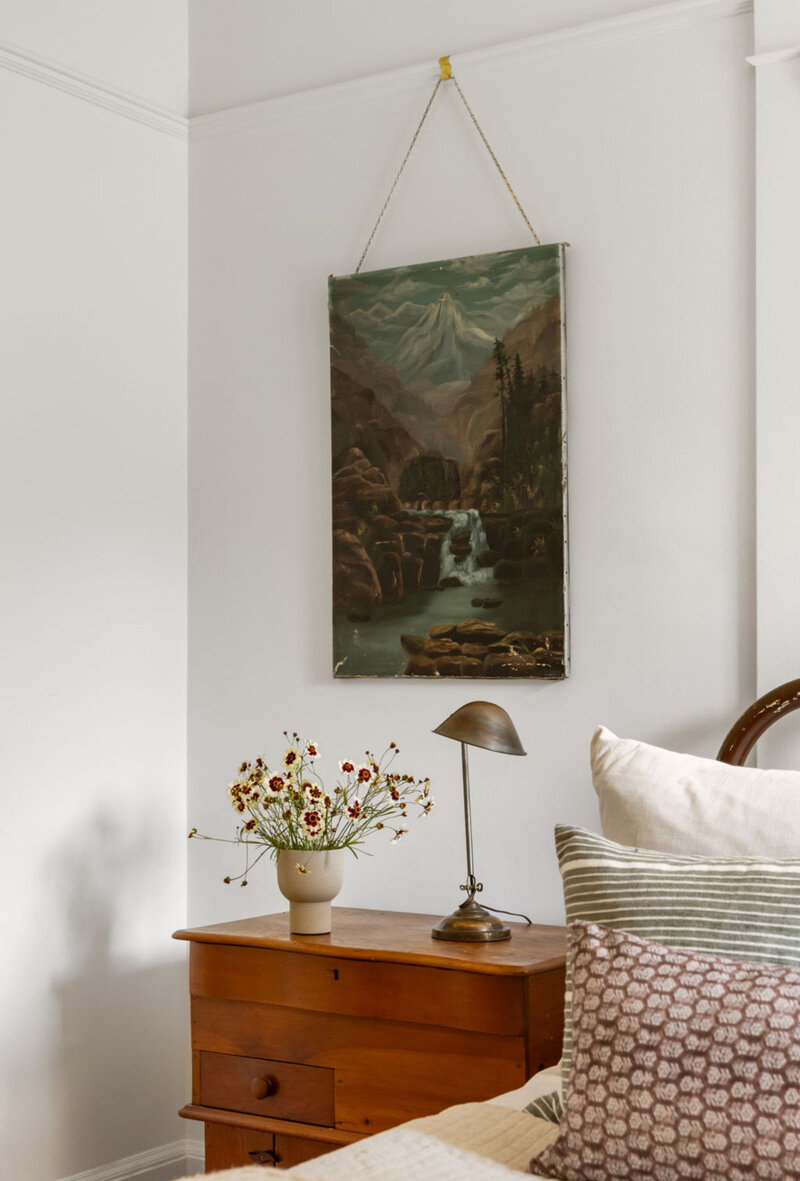 A painting hangs on the wall above a side table with a lamp and vase of flowers, showcasing the staging services offered by Portland OR realtor Stephanie Needham.  