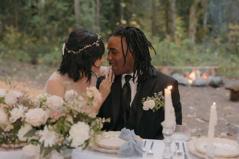 Bride and groom sharing a sweet, joyful moment at their wedding table