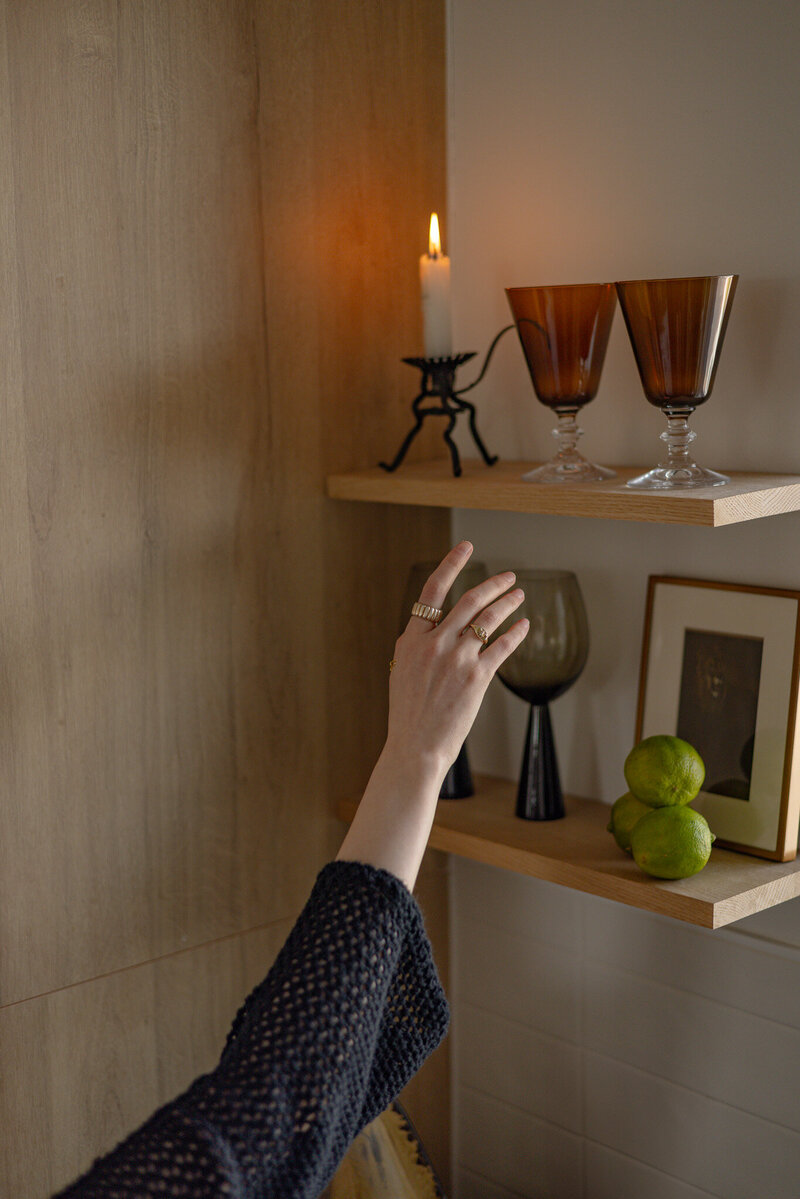 Close-up of kitchen open shelving styled with vintage wine glasses, framed art, and curated decor pieces, designed by Sister Studio.
