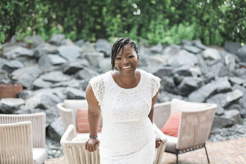 woman mindset coach for women entrepreneurs standing outdoors on a patio and laughing, wearing a white lace summer dress, photo by My Brand Photographer