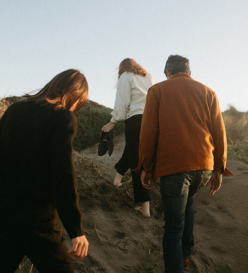A family walks up a sand dune together in San Francisco